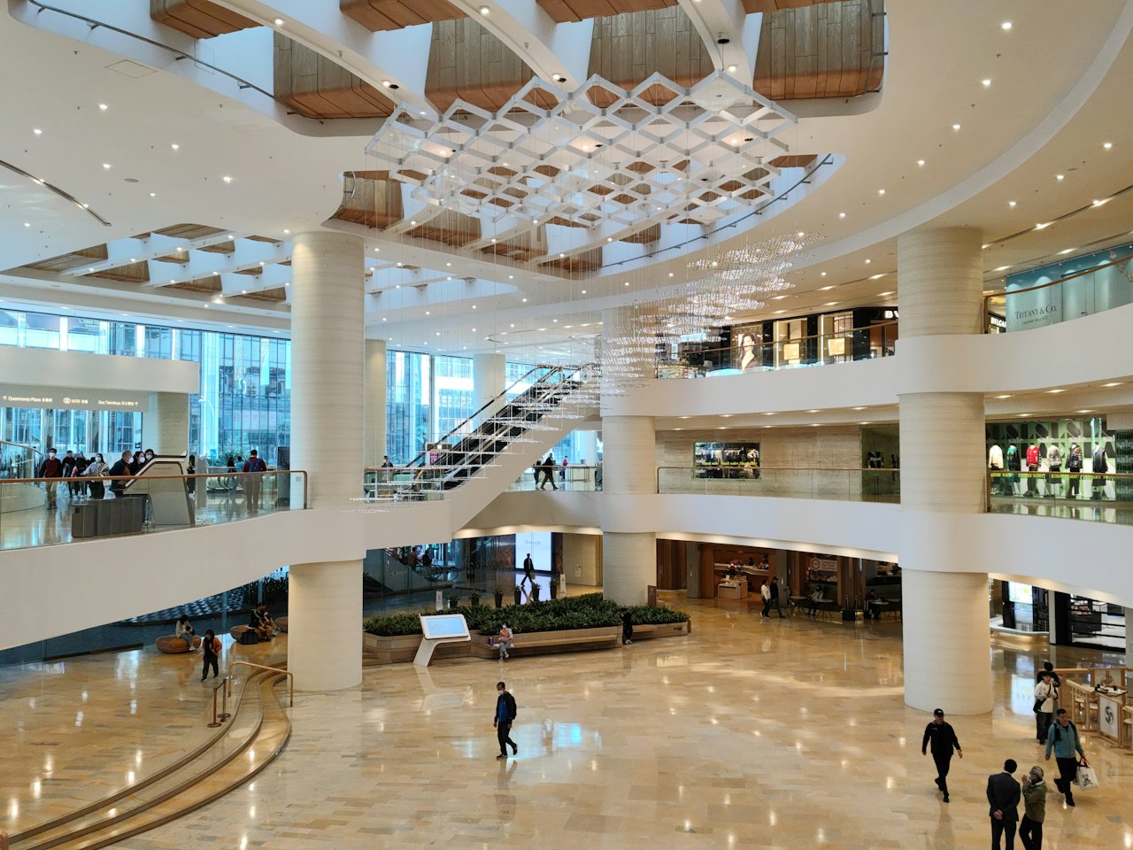 A bright multi-level shopping mall atrium with visitors
