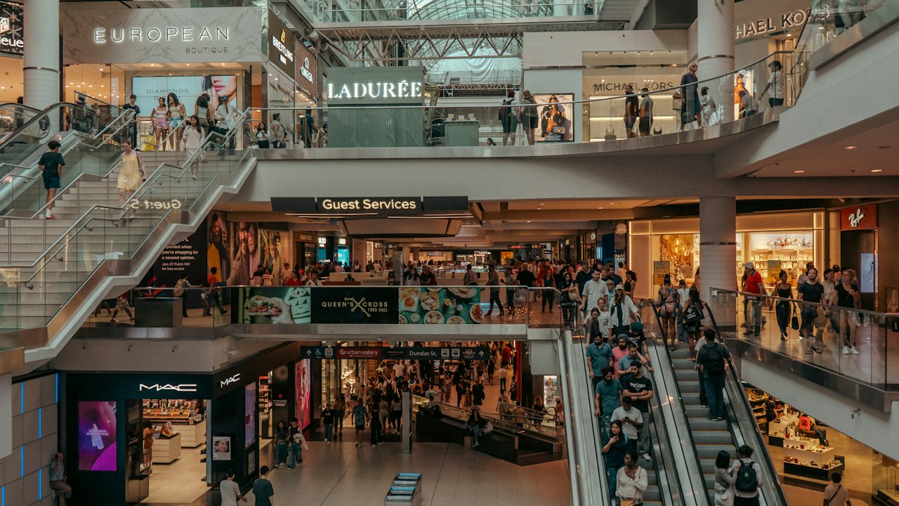 Shoppers and escalators inside a busy mall
